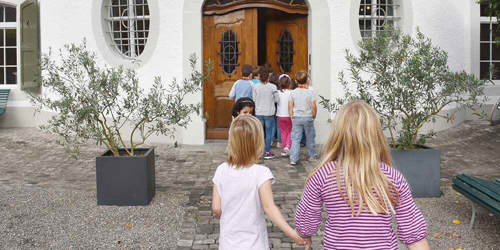 Kindern spazieren Hand in Hand ins Naturmuseum und Museum für Archäologie