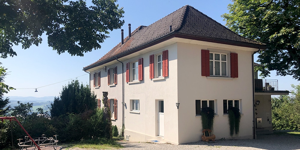 Blick auf das erhöht gelegene Restaurant Thurberg mit schattigen Bäumen und das dahinterliegende Thurtal